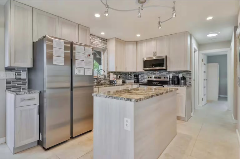 Modern kitchen with white cabinets, stainless steel appliances, granite countertops, and center island with seating area