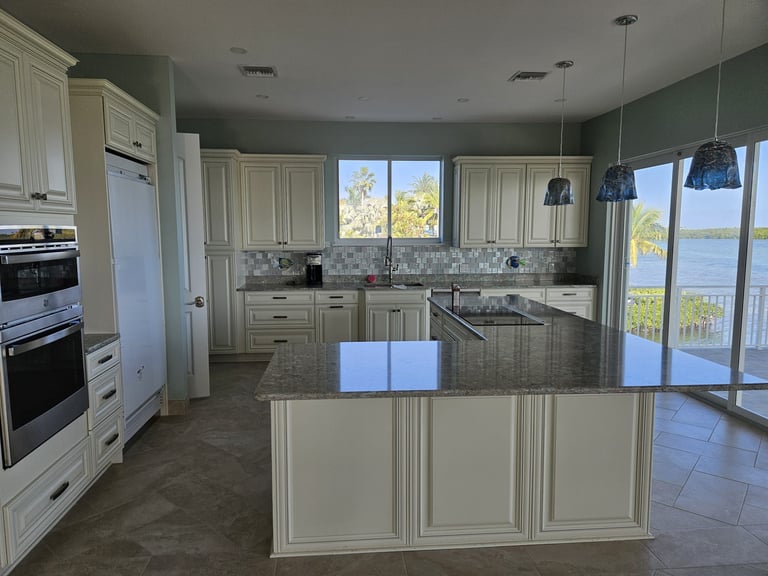 Modern kitchen with cream cabinets, granite countertops, stainless steel appliances, and waterfront views